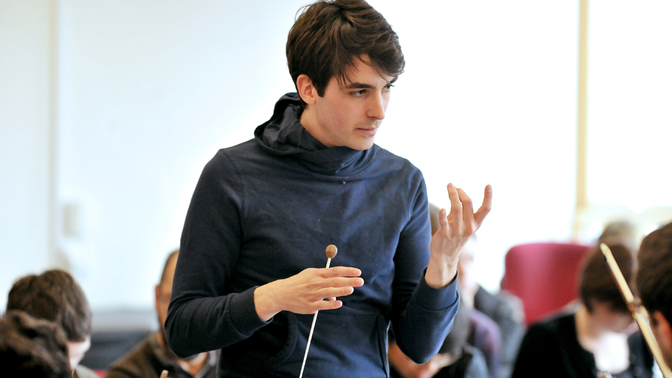 Student conductor talks to an ensemble during a conducting class